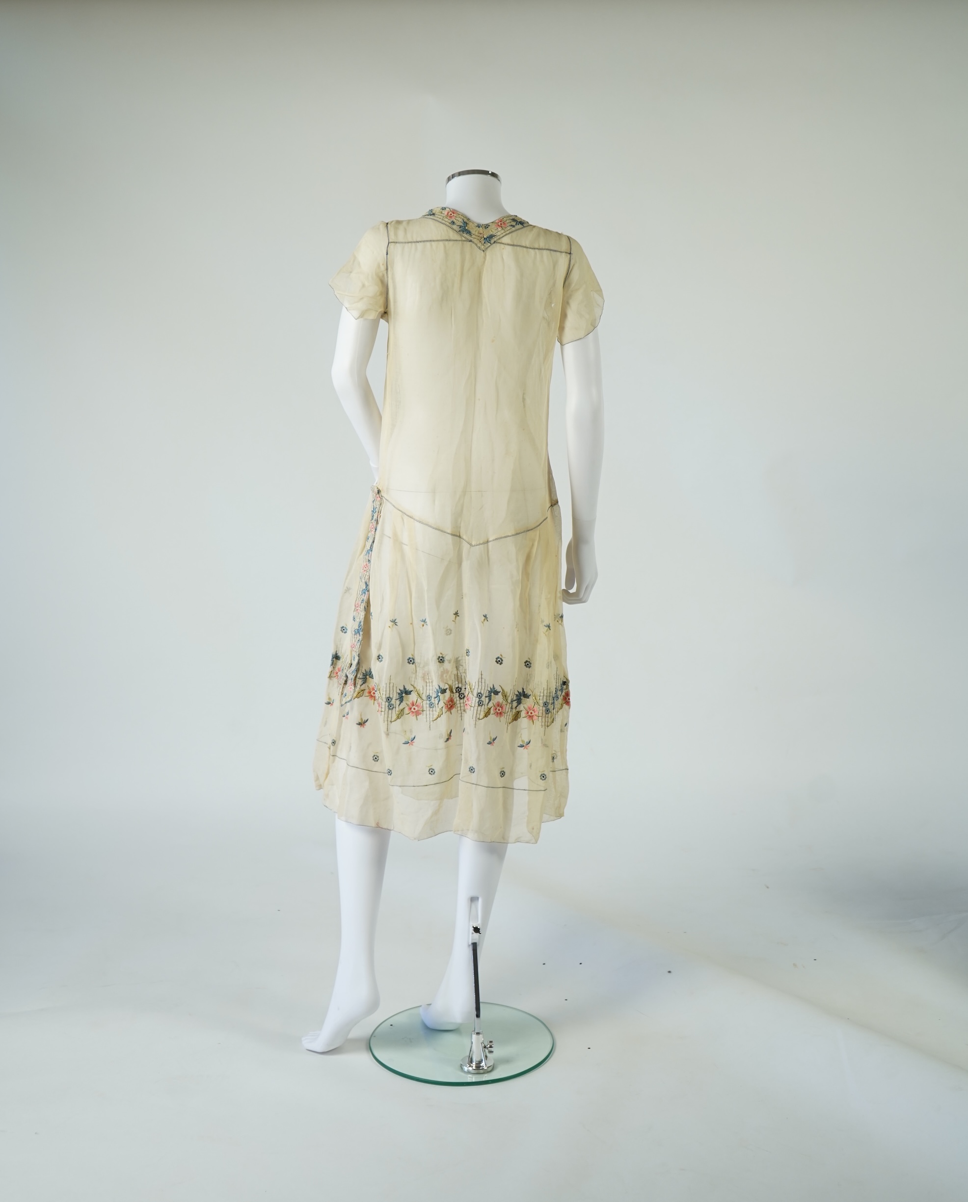 An unusual 1920's fine cream lawn summer dress with hand embroidered blue, pink, flowers, tie and picot edging., 116cm long. Condition - some small rust stains and one small tear at the back right shoulder.